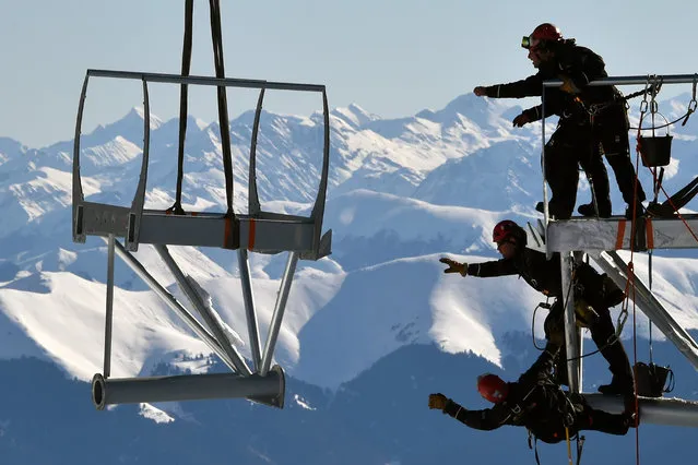 Technicians reach out to catch a piece of a metal structure during the installation of a 12-meter-long platform at the top of the Pic du Midi, one of France's tallest mountains, in Bagneres-de-Bigorre on January 30, 2018. (Photo by Pascal Pavani/AFP Photo)