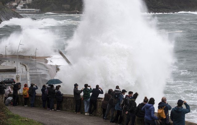 People observe waves crashing on a seaside promenade in the northern Spanish Basque city of San Sebastian on November 22, 2022. Alerts have been issued for dangerous waves along the Basque coast. (Photo by Ander Gillenea/AFP Photo)