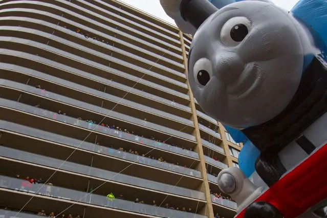 The Thomas the Tank Engine balloon floats by people on balconies during the 88th Annual Macy's Thanksgiving Day Parade in New York November 27, 2014. (Photo by Andrew Kelly/Reuters)