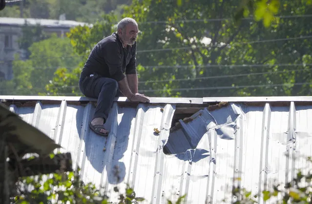 A man examines damage of the roof of his house after shelling by Azerbaijan's artillery, during a military conflict in Stepanakert, the separatist region of Nagorno-Karabakh, Saturday, October 10, 2020. Armenia and Azerbaijan have agreed to a Russia-brokered cease-fire in Nagorno-Karabakh after two weeks of heavy fighting that marked the worst outbreak of hostilities in the separatist region in more than a quarter-century. (Photo by AP Photo/Stringer)