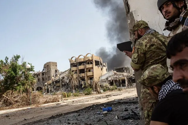 Fighters of the Libyan forces affiliated to the Tripoli government use a broken mirror to observe the movement of Islamic State group members as smoke rises from District 3, the last stronghold of the Islamic State (IS) group in Sirte, on October 2, 2016. A Dutch journalist was killed by sniper fire while covering clashes in Libya's coastal city of Sirte, as unity government forces battled Islamic State group holdouts in the jihadist bastion. (Photo by Fabio Bucciarelli/AFP Photo)