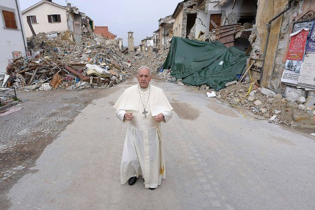 This handout picture released by the Vatican press office on October 4, 2016 shows Pope Francis during a visit in Amatrice, Italy. Pope Francis on October 4, 2016 made a surprise visit to Amatrice, the small Italian mountain town that bore the brunt of the August 24 earthquake that killed nearly 300 people. The Argentinian pontiff's first point of call was a set of colourful pre-fabricated buildings serving as a makeshift school. Amatrice's school was destroyed in the quake despite having been expensively renovated to make it quake resistant a few years ago. (Photo by Osservatore Romano/AFP Photo)