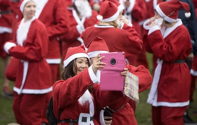 Runners dressed in Santa Claus take a selfie before they compete in the annual Santa Run in Victoria Park, east London December 7, 2014. (Photo by Neil Hall/Reuters)