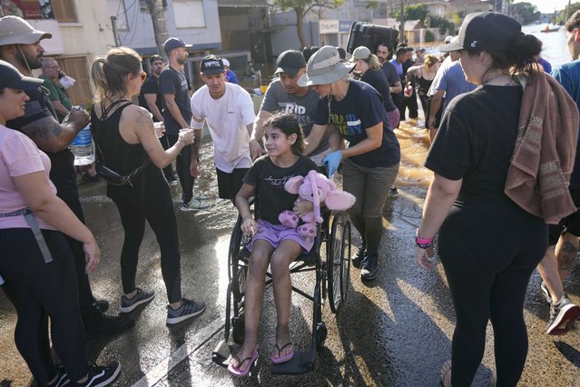 Volunteers push a wheelchair transporting a resident evacuated from an area flooded by heavy rains, in Porto Alegre, Brazil, Tuesday, May 7, 2024. (Photo by Andre Penner/AP Photo)