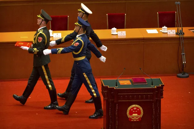 Members of a military honor guard carry a copy of China's constitution after a plenary session of China's National People's Congress (NPC) in Beijing, Saturday, March 17, 2018. Xi Jinping was reappointed Saturday as China's president with no limit on the number of terms he can serve. The National People's Congress, China's rubber-stamp legislature, also appointed close Xi ally Wang Qishan to the formerly ceremonial post of vice president. (Photo by Mark Schiefelbein/AP Photo)