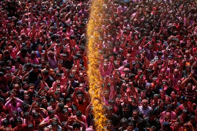 Hindu devotees pray, as they are sprayed with coloured water at a temple's premises, during Holi celebrations in Ahmedabad, India on March 8, 2023. (Photo by Amit Dave/Reuters)