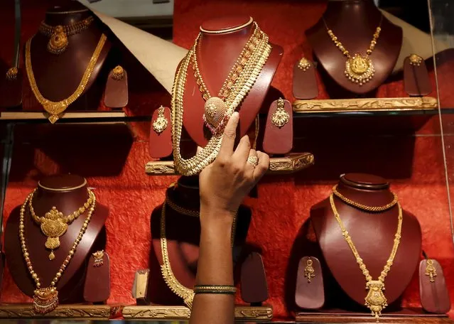 A saleswoman places a gold necklace on a shelf at a showroom in Mumbai, India, August 13, 2015. (Photo by Shailesh Andrade/Reuters)