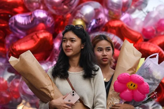 Women walk with bouquets ahead of Valentine's Day at a market in Bangkok, Thailand on February 13, 2023. (Photo by Chalinee Thirasupa/Reuters)