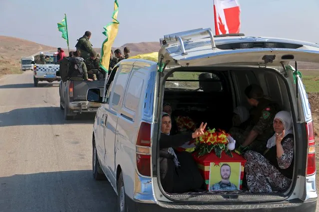 Kurdish People's Protection Units (YPG) fighters drive towards the Iraqi border with the coffin of fellow fighter John Robert Gallagher, a Canadian who died on November 4 in battle with Islamic State fighters, during his funeral in Hasaka, Syria November 12, 2015. (Photo by Rodi Said/Reuters)
