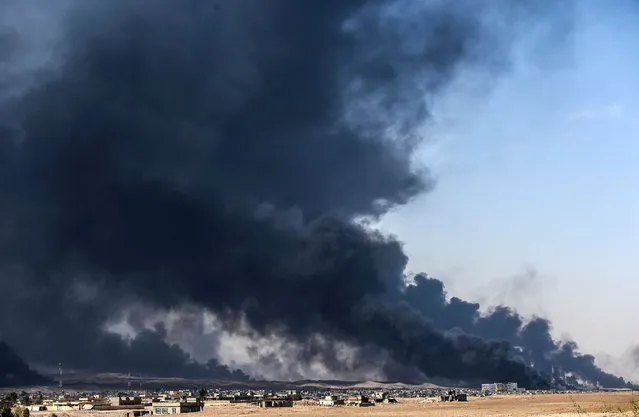 Smoke rises from burning oil wells on October 18, 2016 near the town of Qayyarah, south of Mosul, during the operation to recapture the city from the Islamic State group. (Photo by Bulent Kilic/AFP Photo)