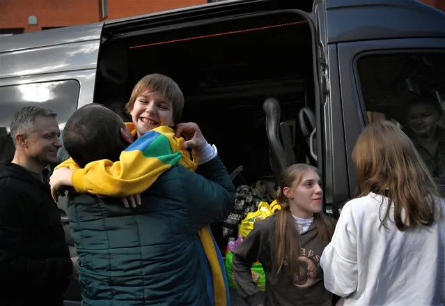 Denys Zaporozhchenko (L) meets his children Nikita, Yana and Dayana (R)  fter the bus delivering them and more than a dozen other children back from Russian-held territory arrived in Kyiv on March 22, 2023. More than 16,000 Ukrainian children have been deported to Russia since the February 24, 2022 invasion, according to Kyiv, with many allegedly placed in institutions and foster homes. (Photo by Sergei Chuzavkov/AFP Photo)