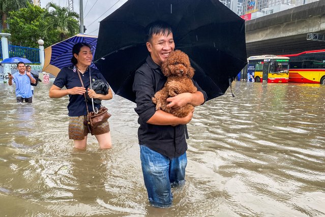 A man carries a dog as he wades through a flooded street amid heavy downpours from Typhoon Matmo, which stranded vehicles, closed schools, moved classes online, and delayed flights to and from Noi Bai International Airport, in Hanoi, Vietnam, on October 7, 2025. (Photo by Thinh Tien Nguyen/Reuters)