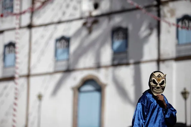 A masked boy walks past Our Lady of the Rosary church, during the “Cavalhadas” festival, in Pirenopolis, Brazil, Sunday, May 19, 2013. The popular festival is a tradition that was introduced in the 1800's by a Portuguese priest to mark the the ascension of Christ. The 3-day festival reenacts the Christian knights' defeat of the Moors. (Photo by Eraldo Peres/AP Photo)