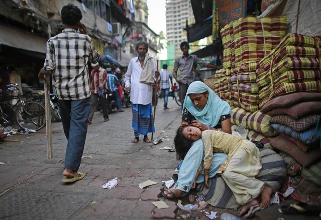 A woman cleans her daughter's hair as she sleeps in her lap by the roadside in Mumbai May 23, 2013. (Photo by Danish Siddiqui/Reuters)