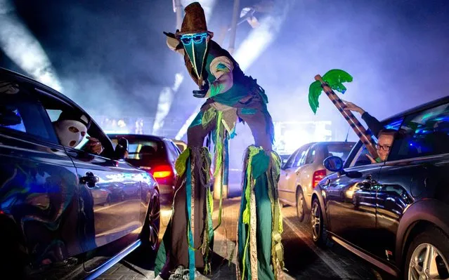 An actor walks on stilts during a car disco across the parking lot of the discotheque “Index” in Schüttorf, Lower Saxony on April 30, 2020. This is the second time that the large-capacity discotheque in Grafschaft Bentheim offers a car disco. A total of 500 guests can participate in 250 vehicles. (Photo by Hauke-Christian Dittrich/dpa)