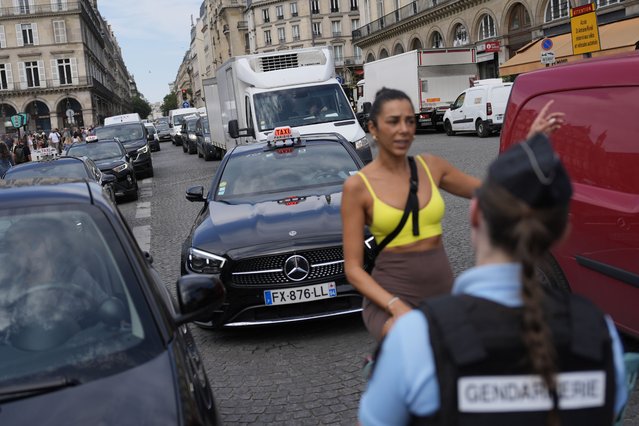 A woman speaks to a police officer at the security perimeter set up for the Olympic Games, Thursday, July 18, 2024, in Paris. (Photo by David Goldman/AP Photo)