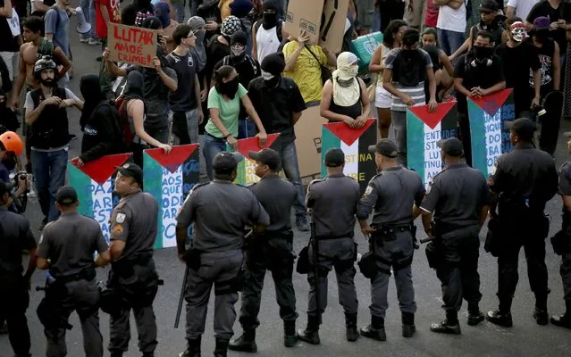 Riot police block a street as demonstrators use makeshift shields painted with the colours of the Palestinian flag during a protest against fare hikes for city buses in Rio de Janeiro January 16, 2015. (Photo by Mauro Pimentel/Reuters)