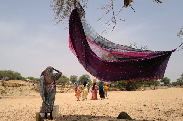 Sudanese women who fled the conflict in Sudan's Darfur region, and were previously internally displaced in Sudan, carry jerrycans of water near the border between Sudan and Chad, while taking refuge in Borota, Chad on May 13, 2023. (Photo by Zohra Bensemra/Reuters)
