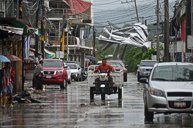 A man rides a motorcycle past to damages on a street as a result of Hurricane John in San Marcos, Guerrero State, Mexico, on September 24, 2024. Two people died in Mexico as a result of John, which made landfall in the Pacific as a category 3 hurricane on September 23 at night but dispersed on Tuesday, while the Mexican Caribbean was declared on alert for storm Helene. (Photo by Francisco Robles/AFP Photo)