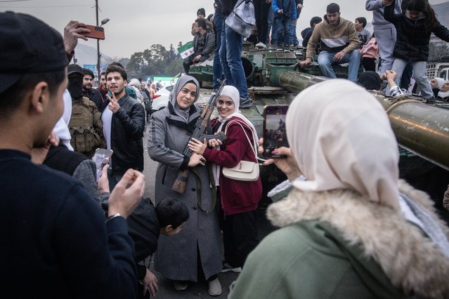 Women pose with a rebel fighter's gun in front of a destroyed tank in Umayyad Square on December 11, 2024 in Damascus, Syria. Rebel forces in Syria have retaken the capital from longtime ruler Bashar al-Assad, who has fled the country for Moscow. The fall of the Assad regime marks a new chapter for Syria, which has been mired in a multi-party civil war since 2011, sparked by the Arab Spring uprisings. (Photo by Chris McGrath/Getty Images)