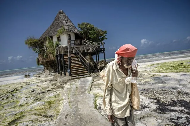 A man walks near a restaurant named “The Rock” at the Pingwe beach near Indian Ocean in Zanzibar, Tanzania on June 30, 2023. Zanzibar Island is a tourist location with its turquoise sea, white sands, spice gardens, natural life parks and street vendors selling fresh fruit with their traditional clothes on the streets. (Photo by Sebnem Coskun/Anadolu Agency via Getty Images)