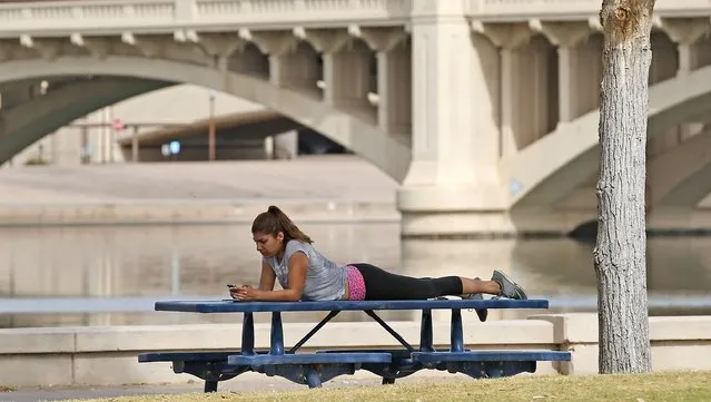 In this October 27, 2106 file photo, a woman relaxes next to Tempe Town Lake as temperatures are expected to break records again, in Tempe, Ariz. While last month merely tied for the world’s third warmest October in history, 2016 is still on track to be the hottest year on record, federal meteorologists said. (Photo by Ross D. Franklin/AP Photo)