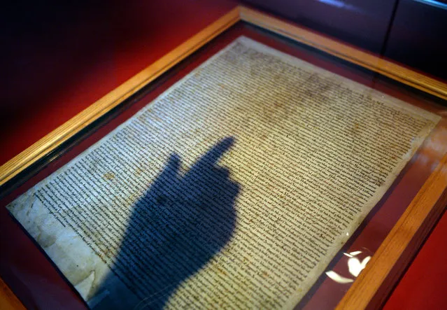 A library employee points at the  Salisbury Magna Carta in The British Library in London, Britain, February 2, 2015. The four surviving original Magna Carta copies were reunited for the first time to mark the 800th anniversary celebrations. (Photo by Facundo Arrizabalaga/EPA)