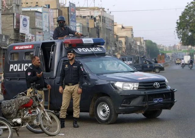 Police officers stand guard at a deserted road due to strikes called by the the country's religious political parties over the security forces's crackdown against a banned Tehreek-e-Labaik Pakistan party, in Karachi, Pakistan, Monday, April 19, 2021. An outlawed Pakistani Islamist political group freed 11 policemen almost a day after taking them hostage in the eastern city of Lahore amid violent clashes with security forces, the country's interior minister said Monday. (Photo by Fareed Khan/AP Photo)