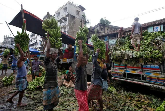 Labourers carry bananas after unloading them from supply trucks at a wholesale fruit market in Kolkata, India, August 29, 2018. (Photo by Rupak De Chowdhuri/Reuters)