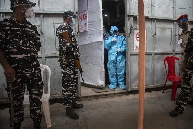 A counting agent in protective suit stands as security men guard during the counting of votes of Assam state assembly election in Gauhati, India, Sunday, May 2, 2021. With Indian hospitals struggling to secure a steady supply of oxygen, and more COVID-19 patients dying amid the shortages, a court in New Delhi said it would start punishing government officials for failing to deliver the life-saving items. (Photo by Anupam Nath/AP Photo)