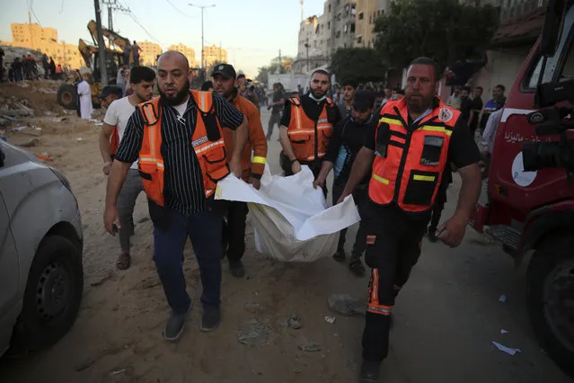 Palestinians carry the body of a child found in the rubble of a house belonging to the Al-Tanani family, that was destroyed in Israeli airstrikes in town of Beit Lahiya, northern Gaza Strip, Thursday, May 13, 2021. (Photo by Abdel Kareem Hana/AP Photo)