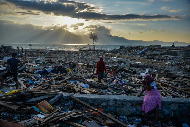 Indonesians stand among debris at Mamboro village in Palu, Central Sulawesi, Indonesia, 05 October 2018. According to the Indonesian National Board for Disaster Management (BNPB) reports, at least 1,571 people have died as a result of a series of powerful earthquakes that hit central Sulawesi on 28 September 2018. (Photo by Iqbal Lubis/EPA/EFE)