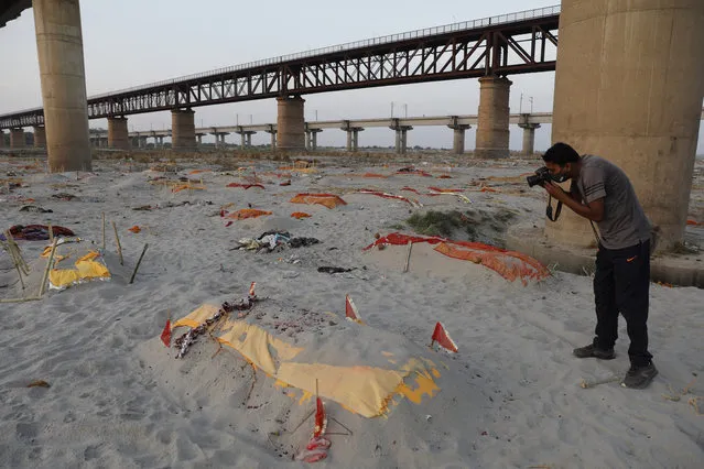 Bodies of suspected Covid-19 victims are seen in shallow graves buried in the sand near a cremation ground on the banks of Ganges River in Prayagraj, India, Saturday, May 15, 2021. (Photo by Rajesh Kumar Singh/AP Photo)