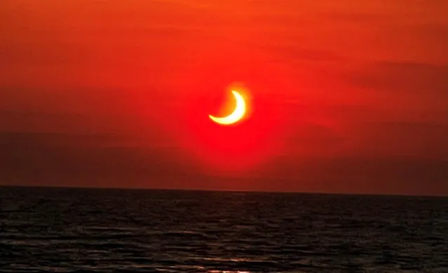 Partial solar eclipse is seen above the horizon in Avon-by-the-Sea, New Jersey, U.S., June 10, 2021 in this picture obtained from a social media. (Photo by Collin Gross via RReuters)