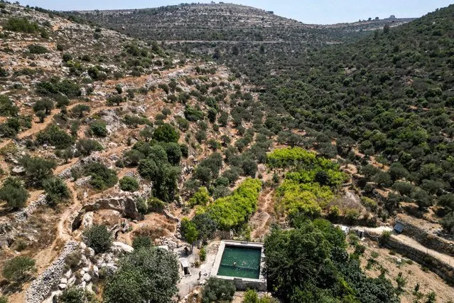 This picture taken on August 18, 2023 shows Palestinian youths swimming in a mountain spring-water pool near the Palestinian village of Deir Ibzi, west of Ramallah in the occupied West Bank. Three decades after the Oslo Accords sprung hopes of Israeli-Palestinian peace, the outdated agreements are roundly seen as a failure which still control even every drop of water. (Photo by Menahem Kahana/AFP Photo)