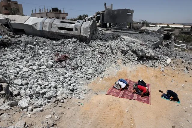 Palestinian Muslim worshippers pray near the rubble of a destroyed mosque in Beit Lahia, in the northern Gaza Strip, on May 27, 2021. A ceasefire was reached late last week after 11 days of deadly violence between Israel and the Hamas movement which runs Gaza, stopping Israel's devastating bombardment on the overcrowded Palestinian coastal enclave which, according to the Gaza health ministry, killed 248 Palestinians, including 66 children, and wounded more than 1,900 people. Meanwhile, rockets from Gaza claimed 12 lives in Israel, including one child and an Israeli soldier. (Photo by Thomas Coex/AFP Photo)