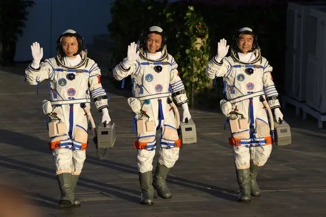 Chinese astronauts, from left, Tang Hongbo, Nie Haisheng, and Liu Boming wave as they prepare to board for liftoff at the Jiuquan Satellite Launch Center in Jiuquan in northwestern China, Thursday, June 17, 2021. China plans on Thursday to launch three astronauts onboard the Shenzhou-12 spaceship who will be the first crew members to live on China's new orbiting space station Tianhe, or Heavenly Harmony. (Photo by Ng Han Guan/AP Photo)