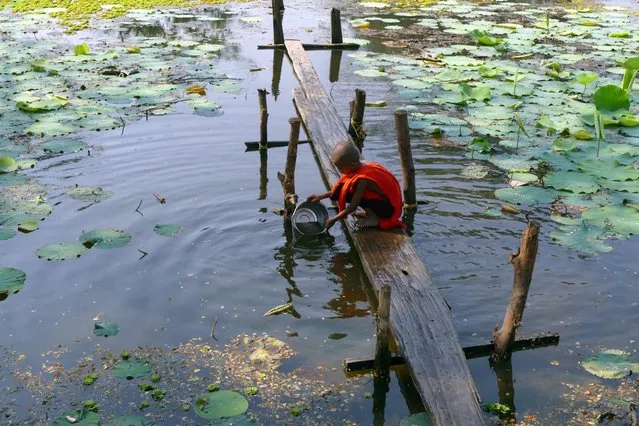 A Buddhist novice monk fetches water from a lake Sunday, March 22, 2015, in Dala Township, 15 kilometers (9 miles) south of Yangon, Myanmar. (Photo by Khin Maung Win/AP Photo)