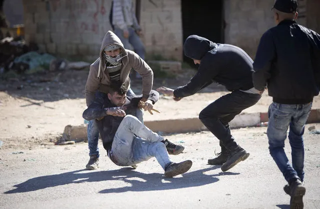 Palestinians help an injured protester sits  during clashes with the Israeli military in the West Bank village of Kabatiya, near Jenin, Thursday, February 4, 2016. Kabatiya is the home village of the three Palestinian men who staged a deadly attack in Jerusalem on Wednesday which  killed a 19-year-old police officer and wounded another. (Photo by Majdi Mohammed/AP Photo)