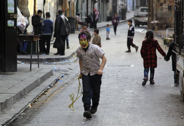 A boy wearing a mask walks along a street in the old city of Aleppo January 26, 2015. (Photo by Jalal Al-Mamo/Reuters)