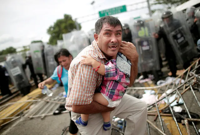 A Honduran migrant protects his child after fellow migrants, part of a caravan trying to reach the U.S., stormed a border checkpoint in Guatemala, in Ciudad Hidalgo, Mexico, October 19, 2018. (Photo by Ueslei Marcelino/Reuters)