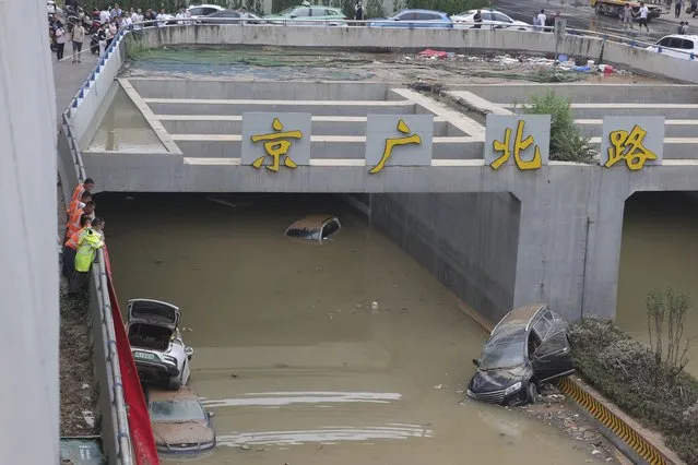 Rescuers watch as water is pumped from a road tunnel feared to be filled with vehicles caught in floodwaters in Zhengzhou in central China's Henan Province, Friday, July 23, 2021. The death toll from catastrophic flooding in the central Chinese city of Zhengzhou has continued to rise, state media reported Friday. The official China Daily newspaper and other media said the number included just Zhengzhou, the capital of Henan province. Other areas of the province have also faced heavy downpours, and rivers and reservoirs burst their banks. (Photo by Chinatopix via AP Photo)