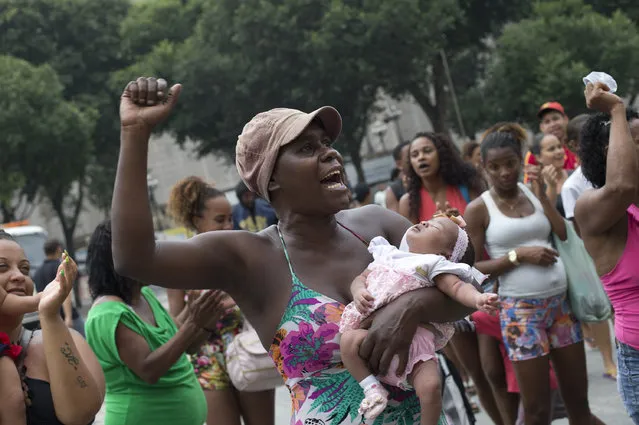 A woman protests the housing shortage and the money spent on the upcoming Olympics Games, and also demands proper housing in Rio de Janeiro, Brazil, Tuesday, March 31, 2015. The demonstrators were evicted recently from a parking lot at the state water and sewage company, CEDAE, where they were living for one week. (Photo by Silvia Izquierdo/AP Photo)