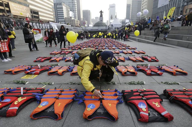 An unidentified mother of the 304 victims of sunken ferry Sewol in 2014 places a light stick on a life vest symbolizing them before a candle light vigil calling for impeached President Park Geun-hye to step down in Seoul, South Korea, Saturday, January 7, 2017. Prosecuting lawmakers accused Park of “broadly and gravely” violating the constitution as the Constitutional Court began hearing oral arguments Thursday in her impeachment trial. (Photo by Ahn Young-joon/AP Photo)