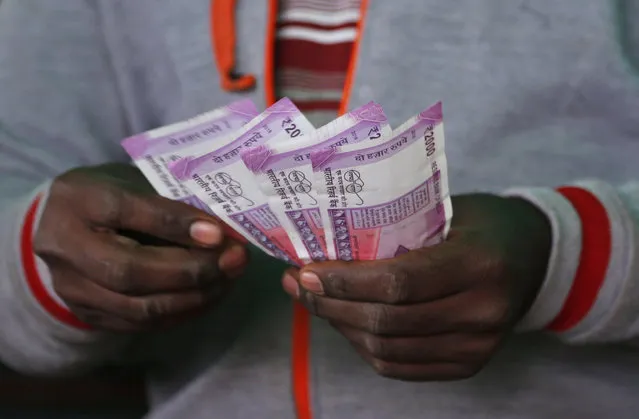 A trader counts new 2,000-rupee notes at a wholesale vegetable market in Bangalore, India, Friday, December 30, 2016. India yanked most of its currency bills from circulation without warning, delivering a jolt to the country's high-performing economy and leaving countless citizens scrambling for cash. Still, as Friday's deadline for depositing old 500- and 1,000-rupee notes draws to a close, Prime Minister Narendra Modi's government has called the demonetization drive a great success in drawing out tax dodgers and eliminating graft. (Photo by Aijaz Rahi/AP Photo)