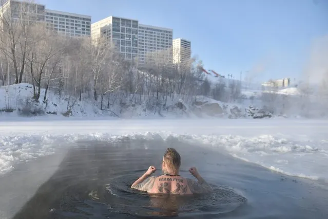 A winter swimming enthusiast swims in an ice hole at a lake in the Siberian city of Novosibirsk with the air temperature at around minus 35 degrees Celsius on December 9, 2023. The tattoo reads “Glory to the Rus (referring to Russia)”. (Photo by Vladimir Nikolayev/AFP Photo)