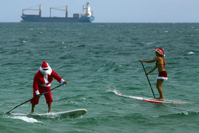 Santa and Mrs Claus, aka Roray Kam and Victoria Burgess, ride the waves off of Ft. Lauderdale, Fla., on Christmas Eve on Tuesday, December 24, 2013. (Photo by Mike Stocker/MCT/ZUMA Press)