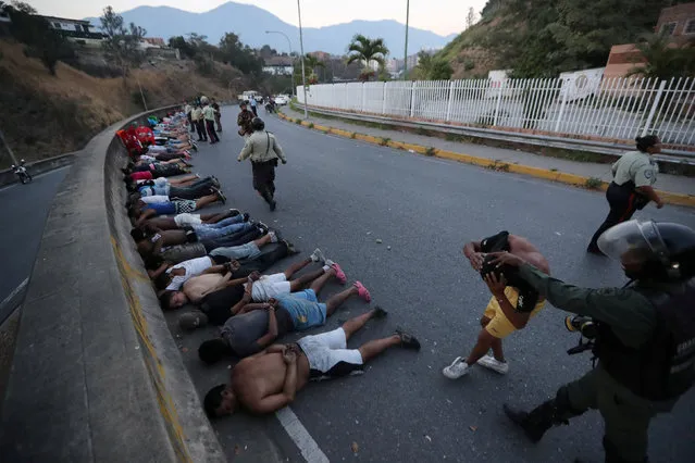People detained by security forces lie on the street after looting broke out during an ongoing blackout in Caracas, Venezuela, March 10, 2019. (Photo by Ivan Alvarado/Reuters)
