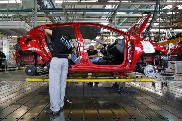 Employees work on the automobile assembly line of a Renault Clio IV at the Renault automobile factory in Flins, west of Paris, France, May 5, 2015. (Photo by Benoit Tessier/Reuters)