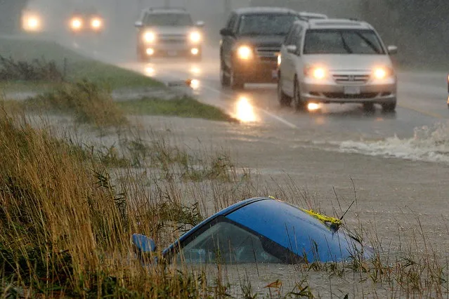 A car lies submerged in a ditch on a flooded stretch of road after rainstorms lashed the western Canadian province of British Columbia, triggering landslides and floods, shutting highways, in Chilliwack, British Columbia, Canada on November 15, 2021. (Photo by Jennifer Gauthier/Reuters)